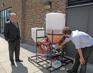 Dr. Danny Monroe (right), head of the VGCC Bioprocess Technology program, describes how his program’s biodiesel production equipment works to U.S. Rep. George Holding (left) during the congressman’s campus tour. (VGCC photo)