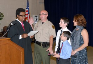 From left, District Court Judge Randolph Baskerville administers the oath of office to VGCC Chief of Police Sean Newton, as his sons, Collin and Anthony, hold the Bible and his wife, Michelle, looks on. (VGCC photo)