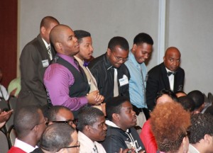 VGCC student David Henry of Macon (left, standing in foreground) speaks on behalf of the group from the college during the N.C. Minority Male Mentoring Conference. Others in the group include, from left, students Lynn Henderson of Henderson, Walter Jefferson of Louisburg and Royston Brown of Henderson, and advisor Anthony Pope. (photo by NC Community College System)