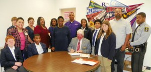 O’Geary is shown in the accompanying photo as he sits at center to sign the proclamation while surrounded by student ambassadors and representatives of the school’s staff.