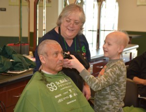 Under the supervision of VGCC Cosmetology instructor Nancy Jackson, 11-year-old Tyler Wallace helps complete the head-shaving for his father, event organizer Tracy Wallace. (VGCC photo)