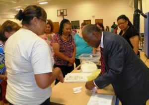 Teachers at New Hope Elementary School gather around Donald McCoy, right, as they help him gather materials for students to make their own hoopsters in a STEM activity at the school.