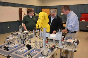 From left, VGCC Electronics Engineering Technology program head Wesley Williams, Mechatronics Engineering Technology program head Keith Shearon and Roger Giddens, a consultant from Moultrie Technical College in Georgia, examine the specifications on new equipment in VGCC's Mechatronics Lab. The Fanuc robot (featuring a bright yellow arm) and SMC electro-pneumatic manufacturing training system are used by students to troubleshoot automation system problems. (VGCC photo)