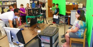 Edward Ortega, a faculty member at Aycock Elementary School, is shown at the far left as he directs students who are news anchors during the "Aycock News" broadcast on October 9.