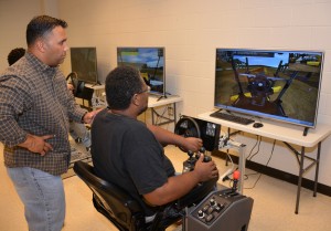 VGCC Heavy Equipment Operator instructor Jason Jones (standing) gives pointers to student Maurice Thorpe, a Granville County resident, as he trains on a motor grader simulator in a classroom on the college’s Warren County Campus. (VGCC photo)