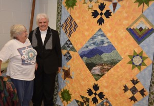 At the Personal Enrichment Open House, VGCC Quilting student Paulette Graham (left) and her instructor, Peggy Stocks of Kerr Lake, enjoy a quilt that Graham made for a competition held in conjunction with the 75th anniversary of Great Smoky Mountains National Park. Graham drives all the way from Raleigh to Henderson to take the quilting class. (VGCC photo)