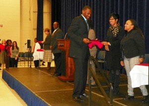 Students walk across the stage and receive recognition certificates.