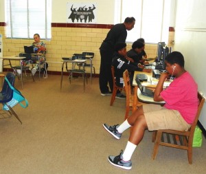 Pictured are Reginald Moore, a teacher at Henderson Middle School, assisting a student with online instruction at the Youth Empowerment Academy.