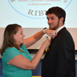 Erica Jastrow, VGCC’s department chair for Nursing, places a pin and ribbon on student Jonathan Carlock during a ceremony at North Carolina A&T State University. (VGCC photo)